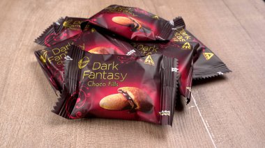 Tahta arka planda paketlenmiş çikolatalı kurabiye yığını.