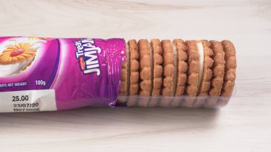 Yanında tatlı reçelli bisküvi paketleri. Sandviç bisküvileri veya ahşap arka planda kremalı bisküviler. 