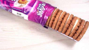 Yanında tatlı reçelli bisküvi paketleri. Sandviç bisküvileri veya ahşap arka planda kremalı bisküviler. 