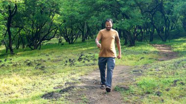 INDIA - 18 HAZİRAN 2021: Yaz parkında yürüyen genç Hintli adamın gündüz çekimi 