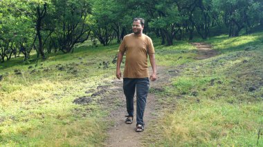 INDIA - 18 HAZİRAN 2021: Yaz parkında yürüyen genç Hintli adamın gündüz çekimi 