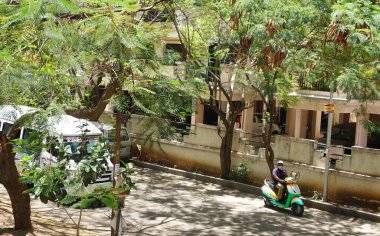 INDIA - 09 Mayıs 2020: Motosikletli Hintli adam megafonla konuşuyor, gündüz vakti kalabalık bir caddede duruyor. 