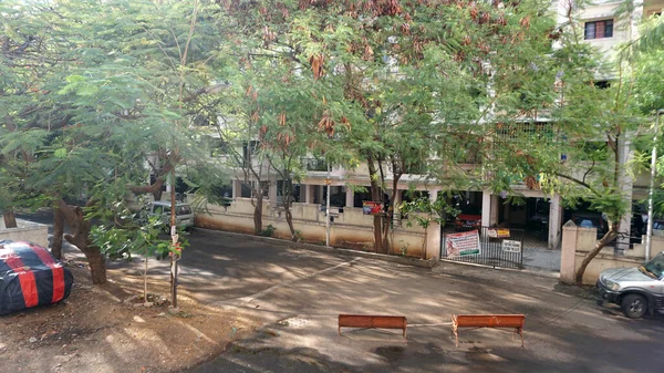 INDIA - 1 Mayıs 2020: Gündüz vakti arabalı ve yeşil ağaçlı Hindistan Caddesi 