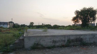 Gün batımında güzel gökyüzü altında yeşil bitkilerle çevrili boş Hint yolu. 