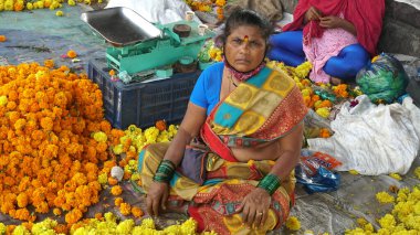 INDIA - 15 Ekim 2021: Hintli çiçek satıcıları ürünlerini gündüz vakti sokak çiçeği pazarında sunuyorlar