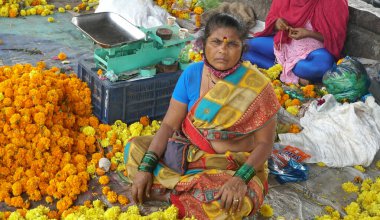 INDIA - 15 Ekim 2021: Hintli çiçek satıcıları ürünlerini gündüz vakti sokak çiçeği pazarında sunuyorlar