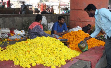 INDIA - 15 Ekim 2021: Hintli çiçek satıcıları ürünlerini gündüz vakti sokak çiçeği pazarında sunuyorlar