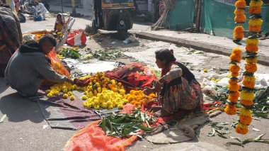 INDIA - 15 Ekim 2021: Hintli çiçek satıcıları ürünlerini gündüz vakti sokak çiçeği pazarında sunuyorlar