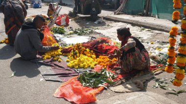 INDIA - 15 Ekim 2021: Hintli çiçek satıcıları ürünlerini gündüz vakti sokak çiçeği pazarında sunuyorlar