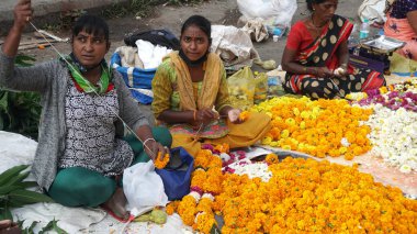 INDIA - 15 Ekim 2021: Hintli çiçek satıcıları ürünlerini gündüz vakti sokak çiçeği pazarında sunuyorlar