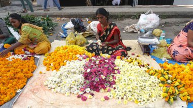 INDIA - 15 Ekim 2021: Hintli çiçek satıcıları ürünlerini gündüz vakti sokak çiçeği pazarında sunuyorlar