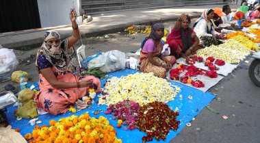 INDIA - 15 Ekim 2021: Hintli çiçek satıcıları ürünlerini gündüz vakti sokak çiçeği pazarında sunuyorlar