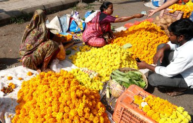 INDIA - 15 Ekim 2021: Hintli çiçek satıcıları ürünlerini gündüz vakti sokak çiçeği pazarında sunuyorlar