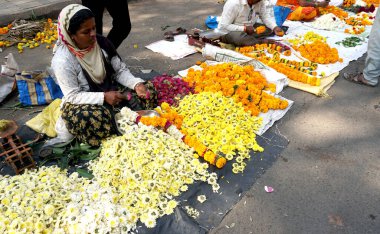 INDIA - 15 Ekim 2021: Hintli çiçek satıcıları ürünlerini gündüz vakti sokak çiçeği pazarında sunuyorlar