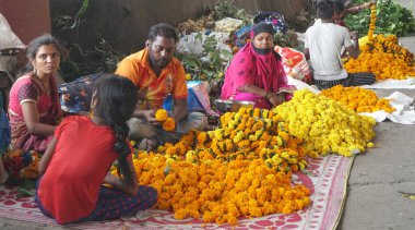 INDIA - 15 Ekim 2021: Hintli çiçek satıcıları ürünlerini gündüz vakti sokak çiçeği pazarında sunuyorlar
