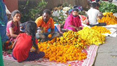 INDIA - 15 Ekim 2021: Hintli çiçek satıcıları ürünlerini gündüz vakti sokak çiçeği pazarında sunuyorlar