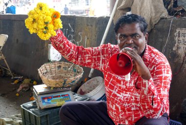 INDIA - 15 Ekim 2021: Hintli çiçek satıcıları ürünlerini gündüz vakti sokak çiçeği pazarında sunuyorlar