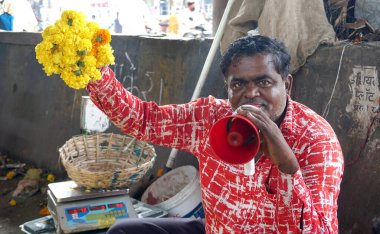 INDIA - 15 Ekim 2021: Hintli çiçek satıcıları ürünlerini gündüz vakti sokak çiçeği pazarında sunuyorlar