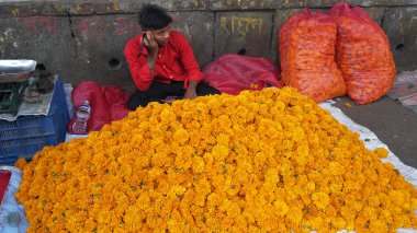 INDIA - 15 Ekim 2021: Hintli çiçek satıcıları ürünlerini gündüz vakti sokak çiçeği pazarında sunuyorlar