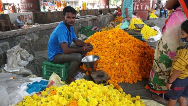 INDIA - 15 Ekim 2021: Hintli çiçek satıcıları ürünlerini gündüz vakti sokak çiçeği pazarında sunuyorlar