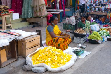 INDIA - 15 Ekim 2021: Hintli çiçek satıcıları ürünlerini gündüz vakti sokak çiçeği pazarında sunuyorlar