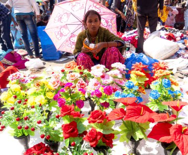 INDIA - 20 Şubat 2022: Hintli kadın satıcı sokak pazarında şemsiye altında oturuyor
