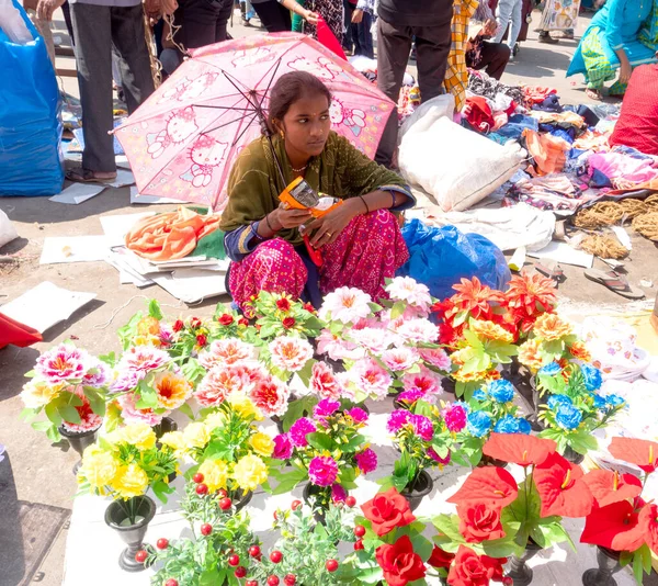 INDIA - 20 Şubat 2022: Hintli kadın satıcı sokak pazarında şemsiye altında oturuyor