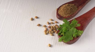 Kuru kişniş tohumları ile küçük bambu kaşıkları ve yeşil demet kişniş yaprakları, Asya mutfağında ünlü baharatlar..