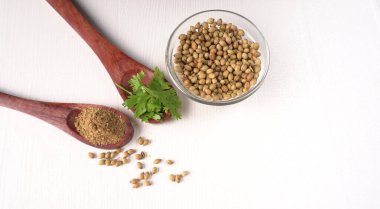 Kuru kişniş tohumları ile küçük bambu kaşıkları ve yeşil demet kişniş yaprakları, Asya mutfağında ünlü baharatlar..