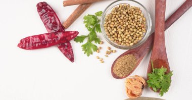 Kuru kişniş tohumları ile küçük bambu kaşıkları ve yeşil demet kişniş yaprakları, Asya mutfağında ünlü baharatlar..