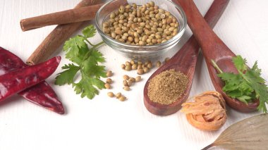 Kuru kişniş tohumları ile küçük bambu kaşıkları ve yeşil demet kişniş yaprakları, Asya mutfağında ünlü baharatlar..