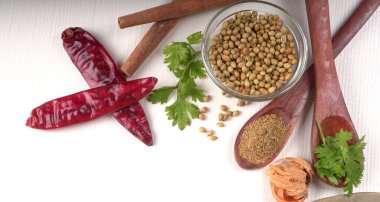 Kuru kişniş tohumları ile küçük bambu kaşıkları ve yeşil demet kişniş yaprakları, Asya mutfağında ünlü baharatlar..