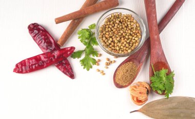 Kuru kişniş tohumları ile küçük bambu kaşıkları ve yeşil demet kişniş yaprakları, Asya mutfağında ünlü baharatlar..