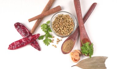 Kuru kişniş tohumları ile küçük bambu kaşıkları ve yeşil demet kişniş yaprakları, Asya mutfağında ünlü baharatlar..