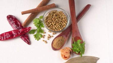 Kuru kişniş tohumları ile küçük bambu kaşıkları ve yeşil demet kişniş yaprakları, Asya mutfağında ünlü baharatlar..