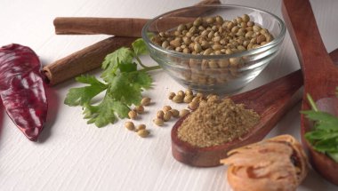 Kuru kişniş tohumları ile küçük bambu kaşıkları ve yeşil demet kişniş yaprakları, Asya mutfağında ünlü baharatlar..