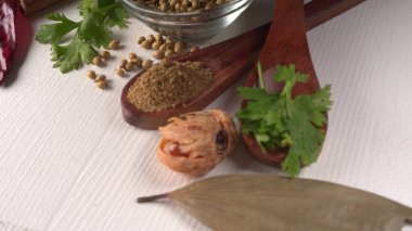 Kuru kişniş tohumları ile küçük bambu kaşıkları ve yeşil demet kişniş yaprakları, Asya mutfağında ünlü baharatlar..