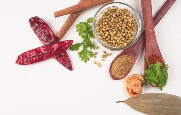 Kuru kişniş tohumları ile küçük bambu kaşıkları ve yeşil demet kişniş yaprakları, Asya mutfağında ünlü baharatlar..