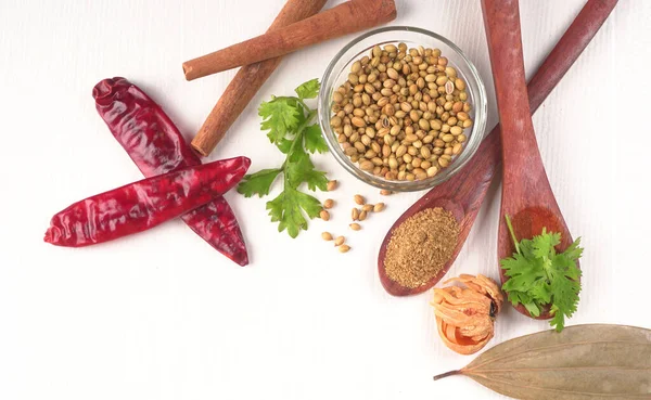 Kuru kişniş tohumları ile küçük bambu kaşıkları ve yeşil demet kişniş yaprakları, Asya mutfağında ünlü baharatlar..