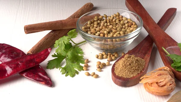 Kuru kişniş tohumları ile küçük bambu kaşıkları ve yeşil demet kişniş yaprakları, Asya mutfağında ünlü baharatlar..