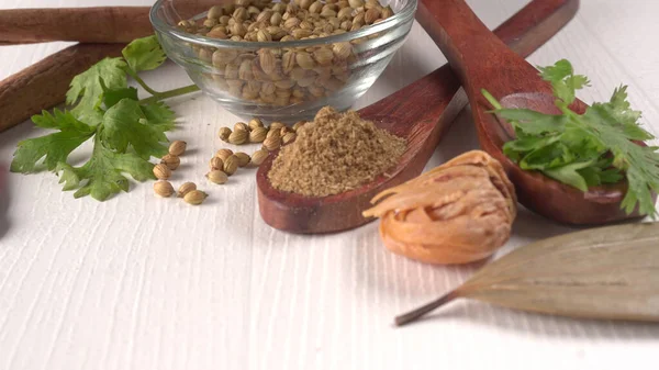 Kuru kişniş tohumları ile küçük bambu kaşıkları ve yeşil demet kişniş yaprakları, Asya mutfağında ünlü baharatlar..