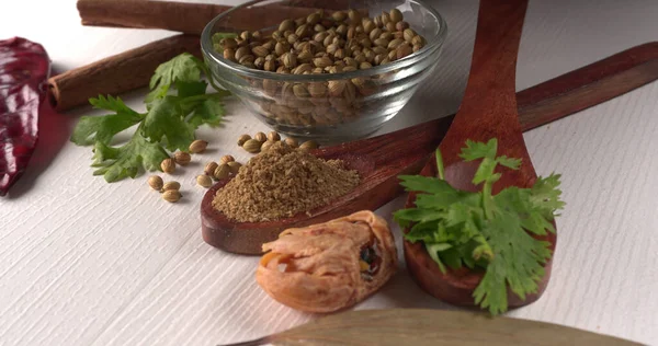 Kuru kişniş tohumları ile küçük bambu kaşıkları ve yeşil demet kişniş yaprakları, Asya mutfağında ünlü baharatlar..