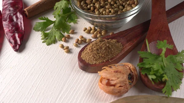 Kuru kişniş tohumları ile küçük bambu kaşıkları ve yeşil demet kişniş yaprakları, Asya mutfağında ünlü baharatlar..