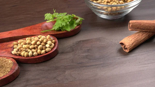 Kuru kişniş tohumları ile küçük bambu kaşıkları ve yeşil demet kişniş yaprakları, Asya mutfağında ünlü baharatlar..