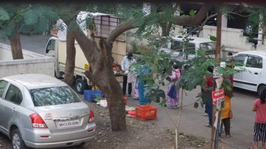 INDIA - 1 Mayıs 2020: Hintliler gündüz vakti arabaları ve yeşil ağaçlarıyla caddelerde hareket ediyorlar 