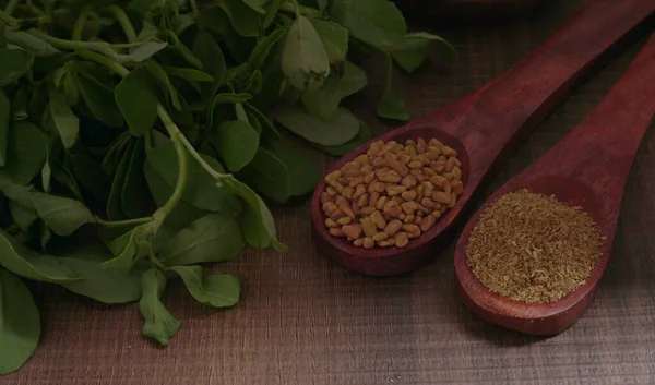 Kuru kişniş tohumları ile küçük bambu kaşıkları ve yeşil demet kişniş yaprakları, Asya mutfağında ünlü baharatlar..