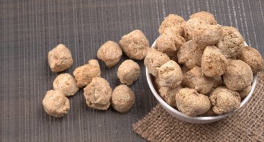 Ahşap arka planda çiğ soya parçaları. Sağlıklı, besleyici soya fasulyesi eti. Vejetaryen gıda konsepti.