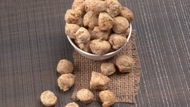 Ahşap arka planda çiğ soya parçaları. Sağlıklı, besleyici soya fasulyesi eti. Vejetaryen gıda konsepti.