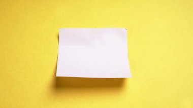 White ripped striped, notebook, note paper for text or message stuck on yellow background.