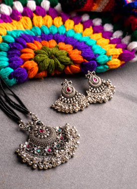 Hint geleneksel antikası ya da renkli örgü arka planda küpeleri olan retro tarzı kolye.